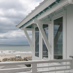 Viiwnco Impact windows in foreground, cloudy beach scene in background.