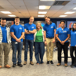 Group of six interns standing with Elena Kollar in blue Viwinco Shirts in the Training Center